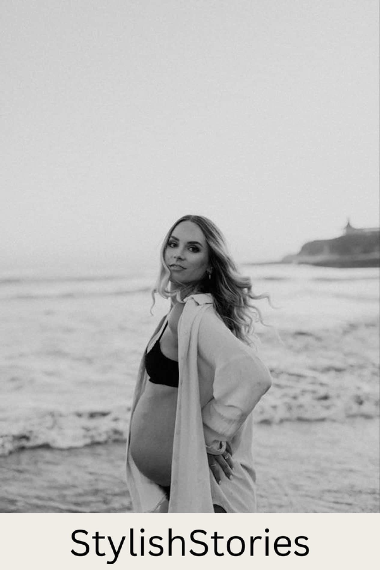 image of a pregnant woman wearing a black bikini and a white overskirt on a beach in black and white