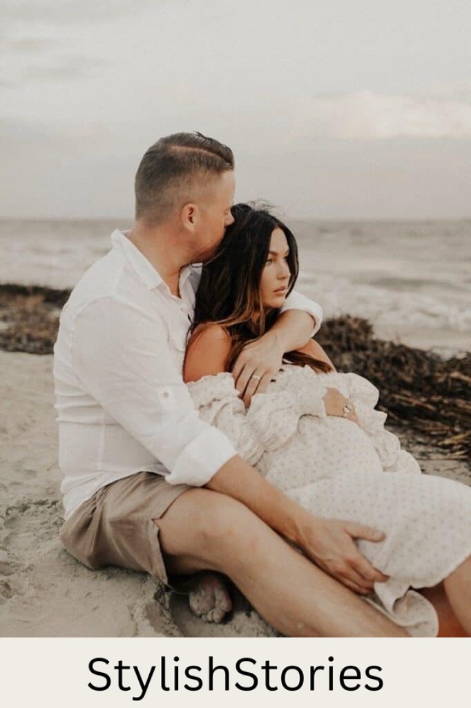 image of a man embracing a pregnant woman with a rocky coast beach in the background