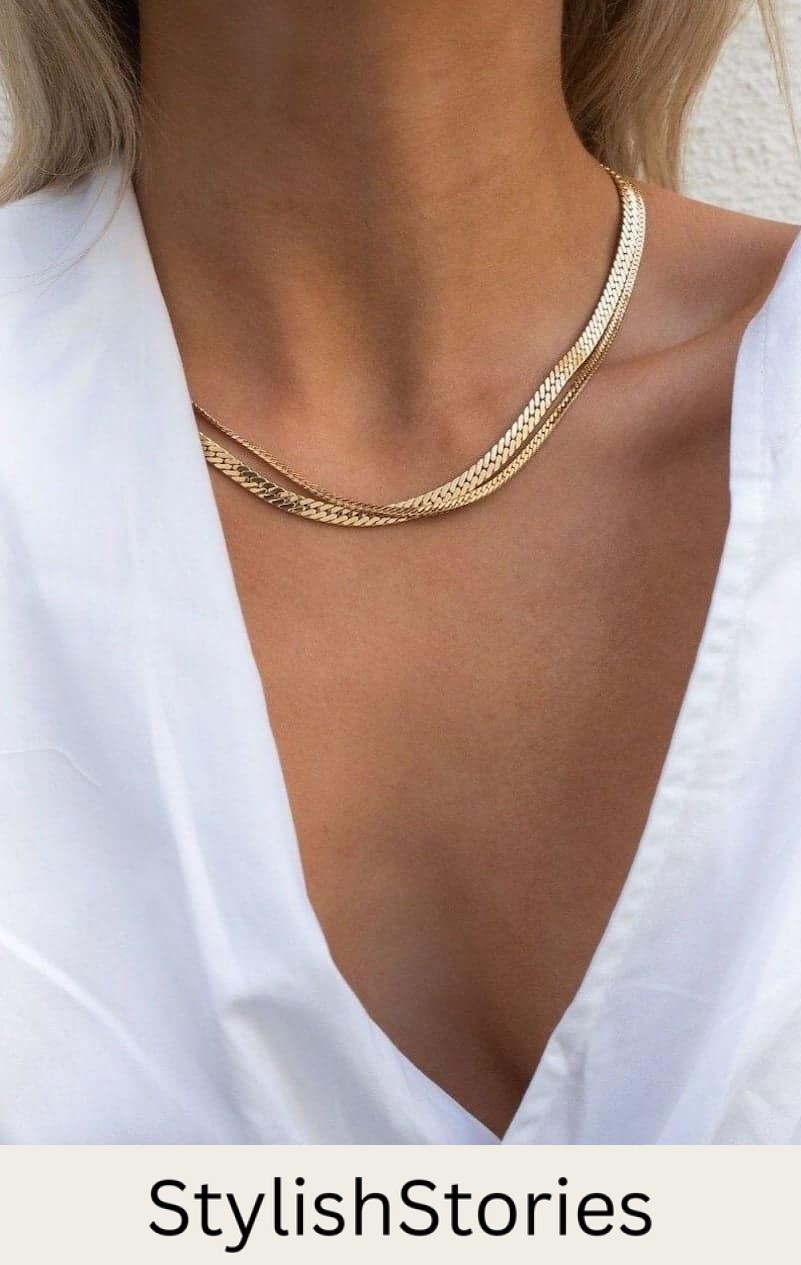 Close up shot of a woman wearing two gold chain necklaces.
