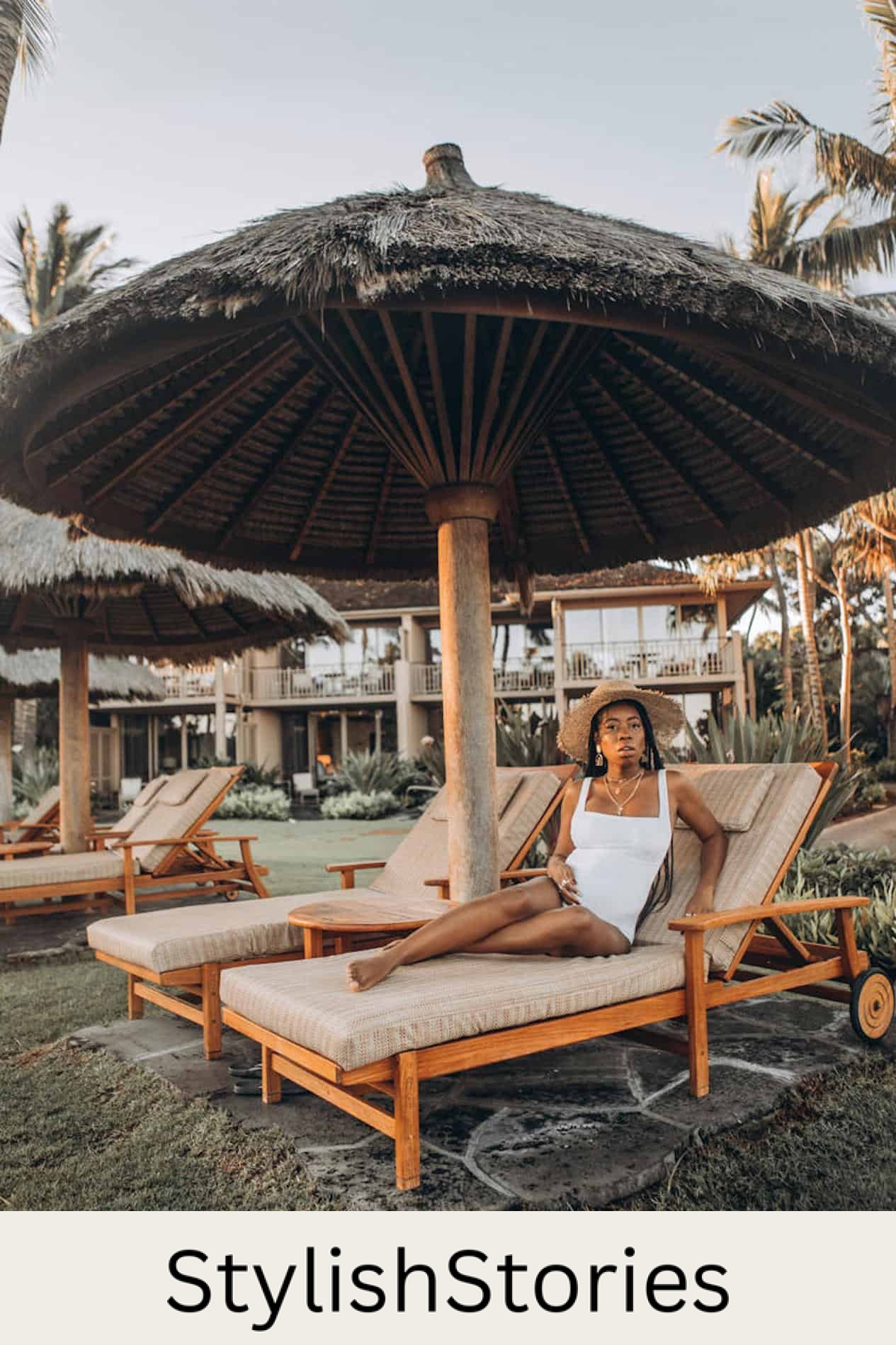 image of a pregnant black woman in a white swimsuit sitting on a lounge chair on a beach with a resort in the background