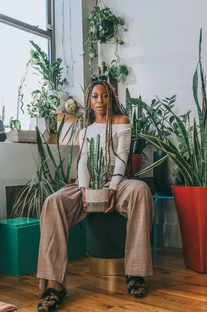 an image of black woman sitting surrounded by plants