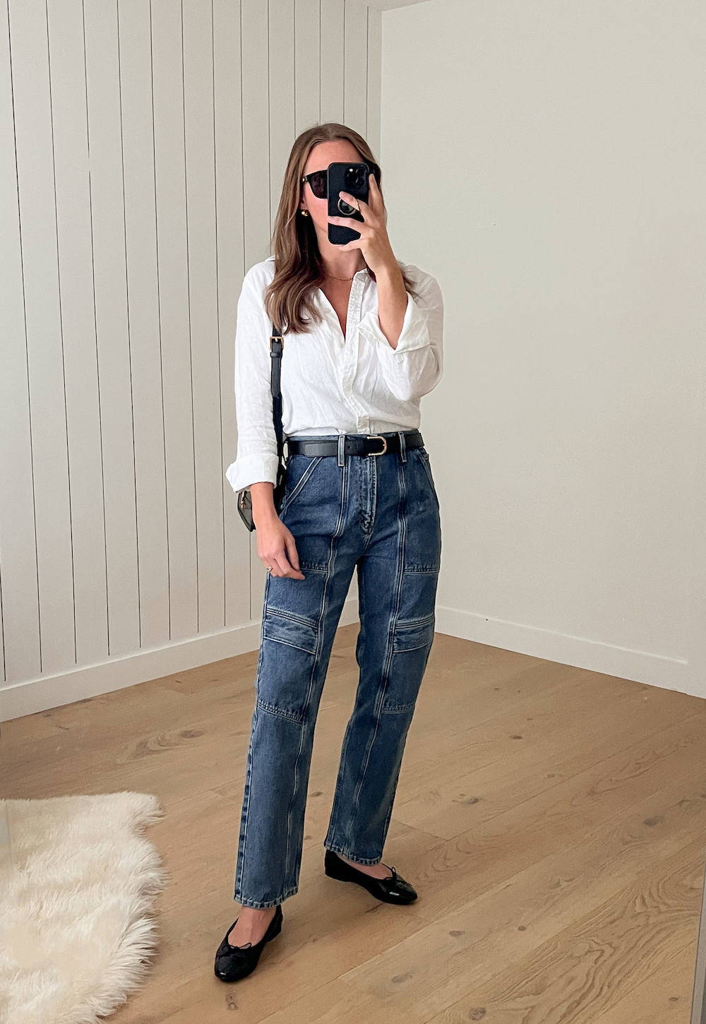 Woman wearing utility jeans and ballet flats with a white button down.