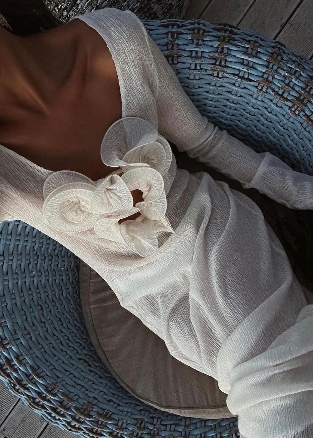 an overhead shot of a woman wearing a sheer white long-sleeved maxi dress with a floral neckline