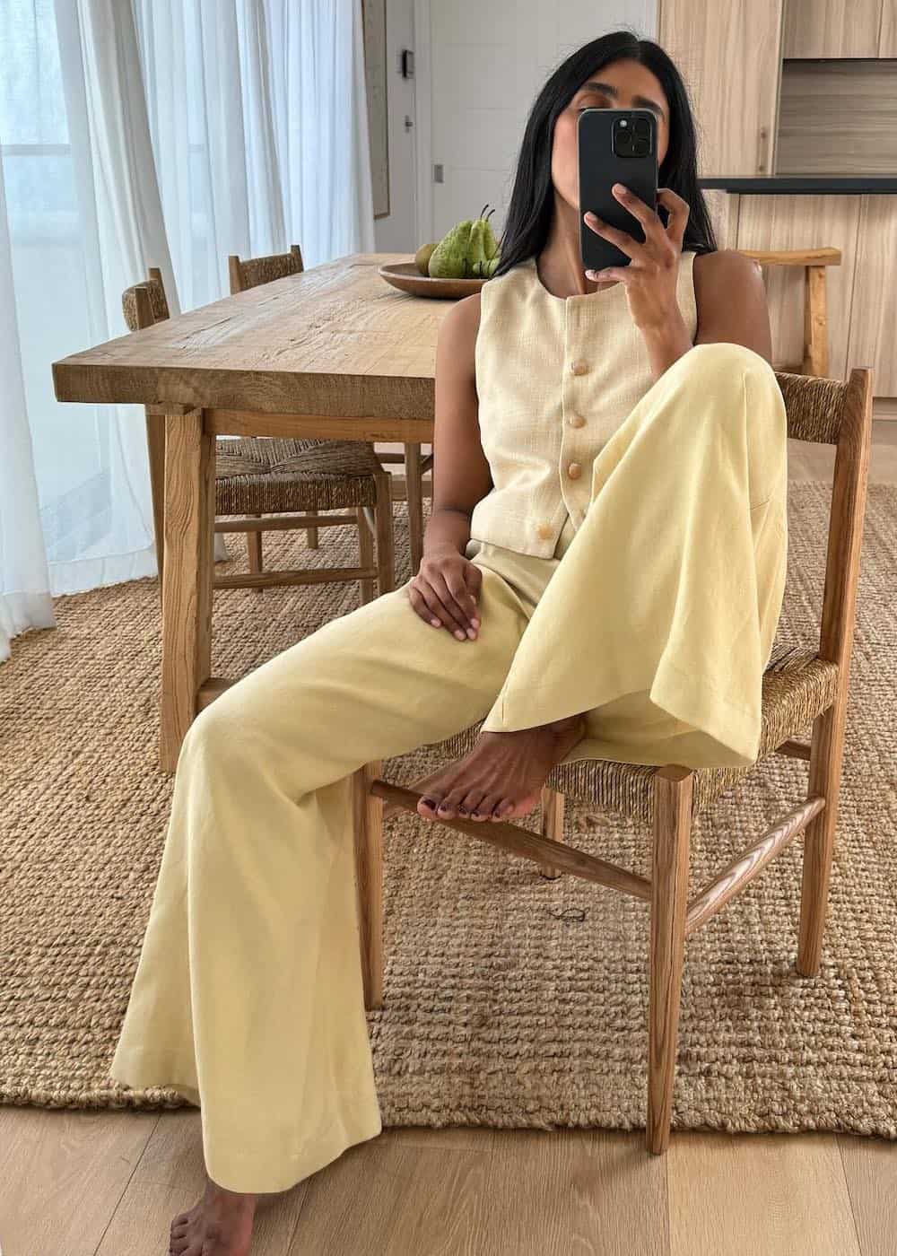 a woman wearing a butter yellow matching set featuring wide leg pants and a button-up vest
