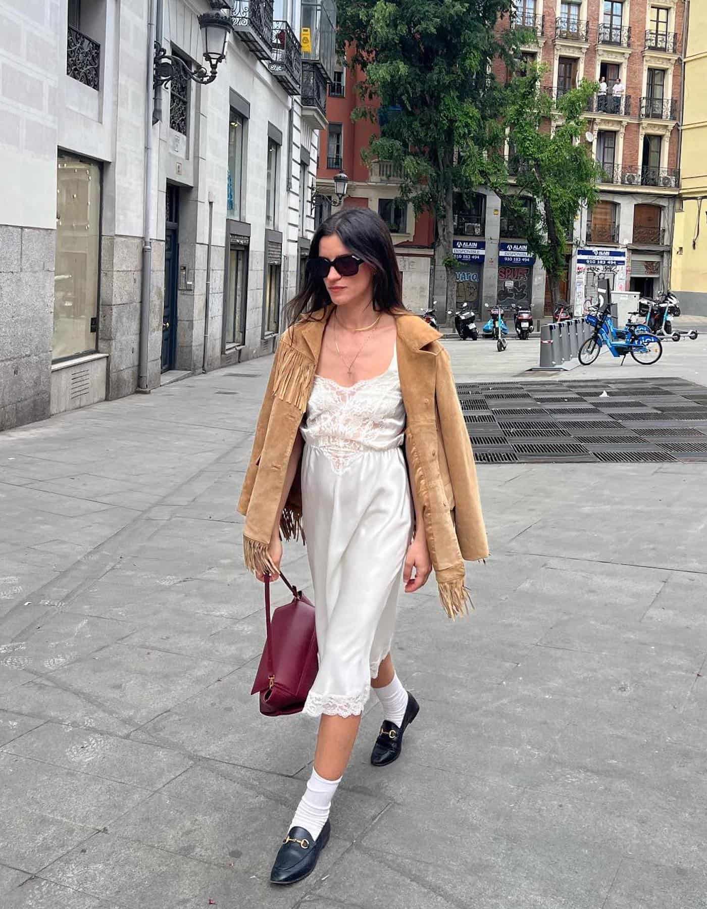 Woman wearing a satin slip dress with a fringe jacket.