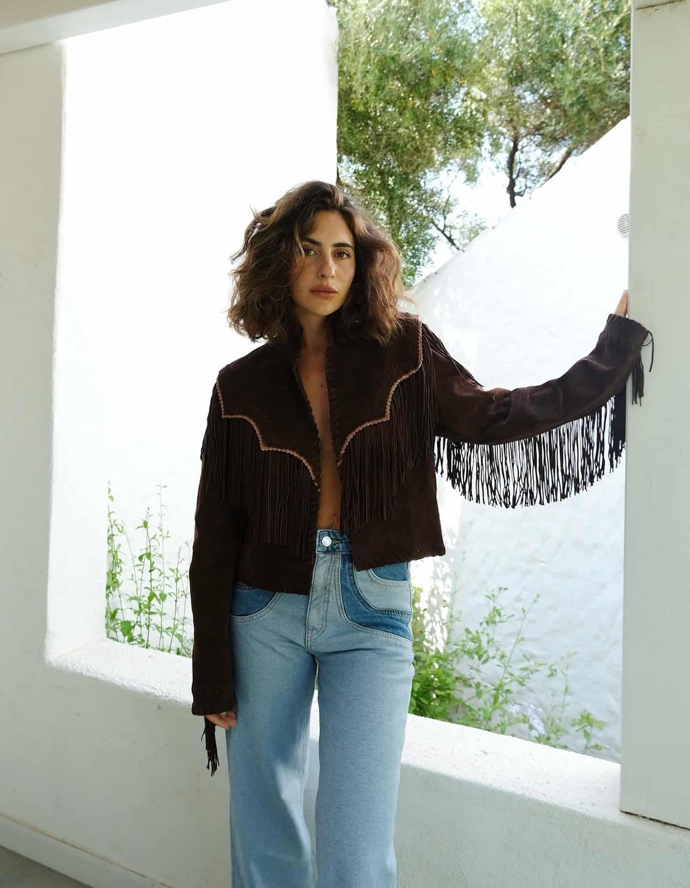 Woman wearing jeans with a fringe jacket.