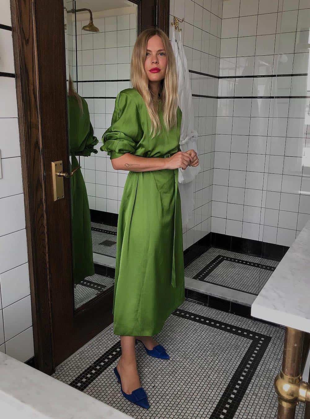 Woman wearing a green satin dress with navy heels.