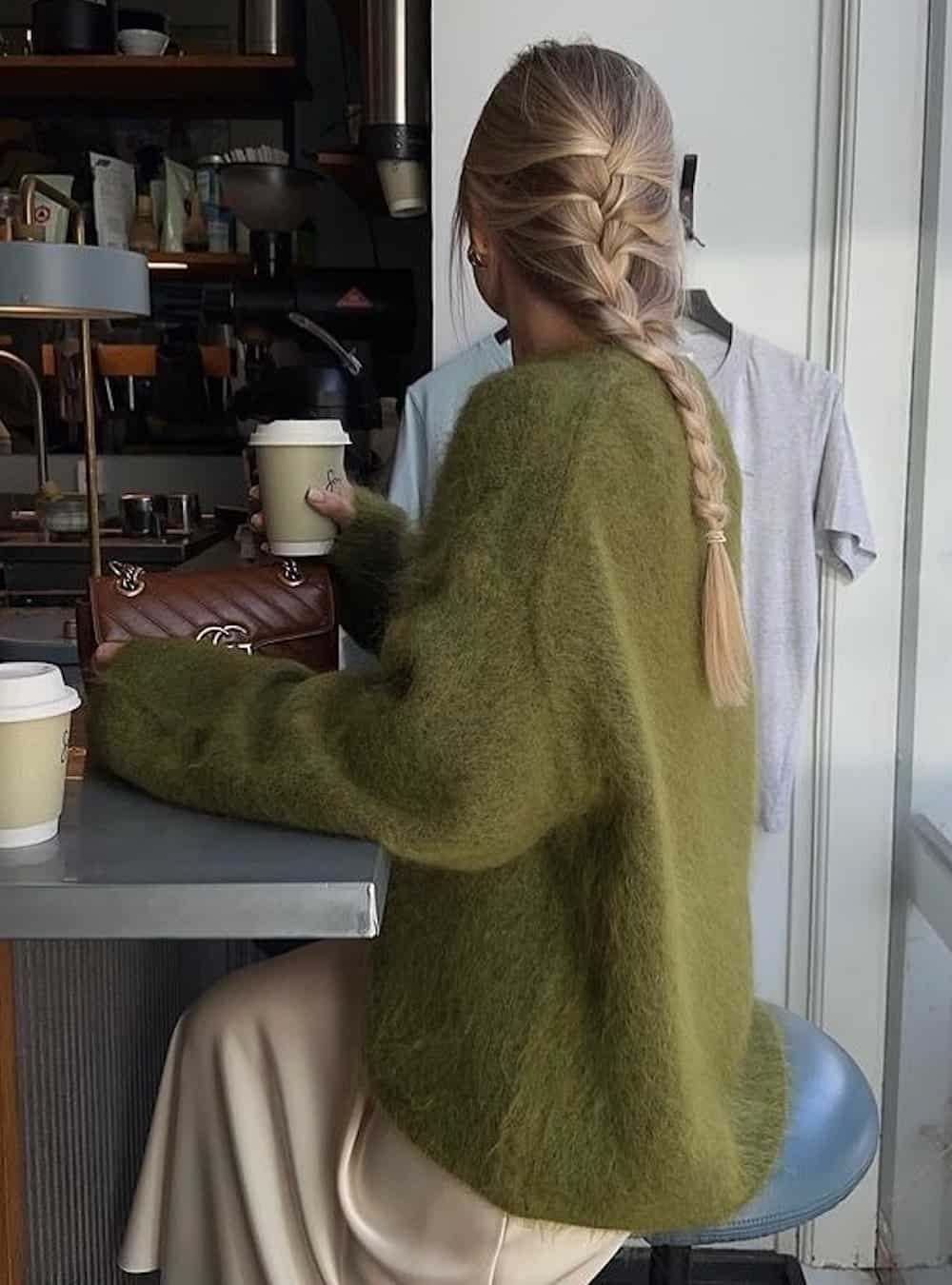 Woman wearing a green eye lash sweater with a satin slip skirt.
