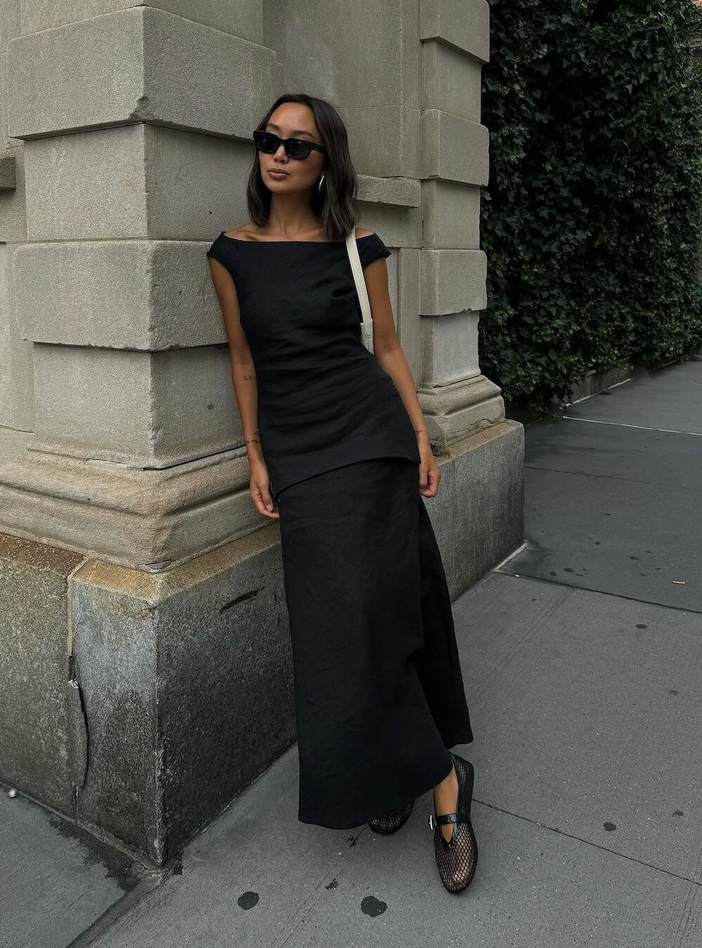 Woman wearing a black, off-the-shoulder midi dress with mesh shoes.