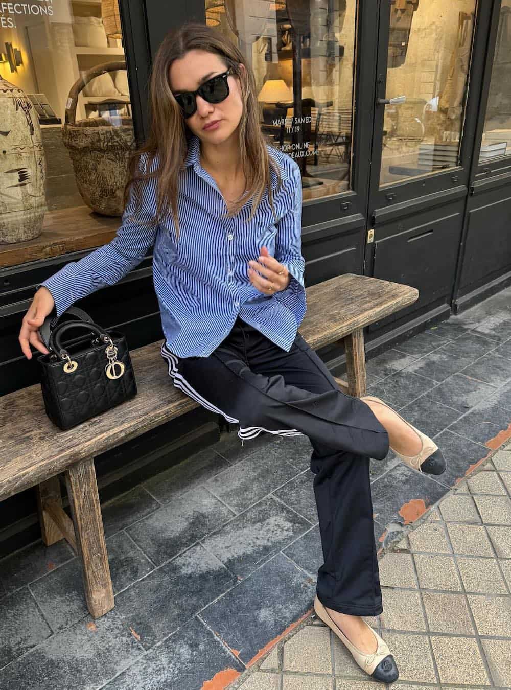 Woman wearing sating pants with a blue button down and ballet flats.