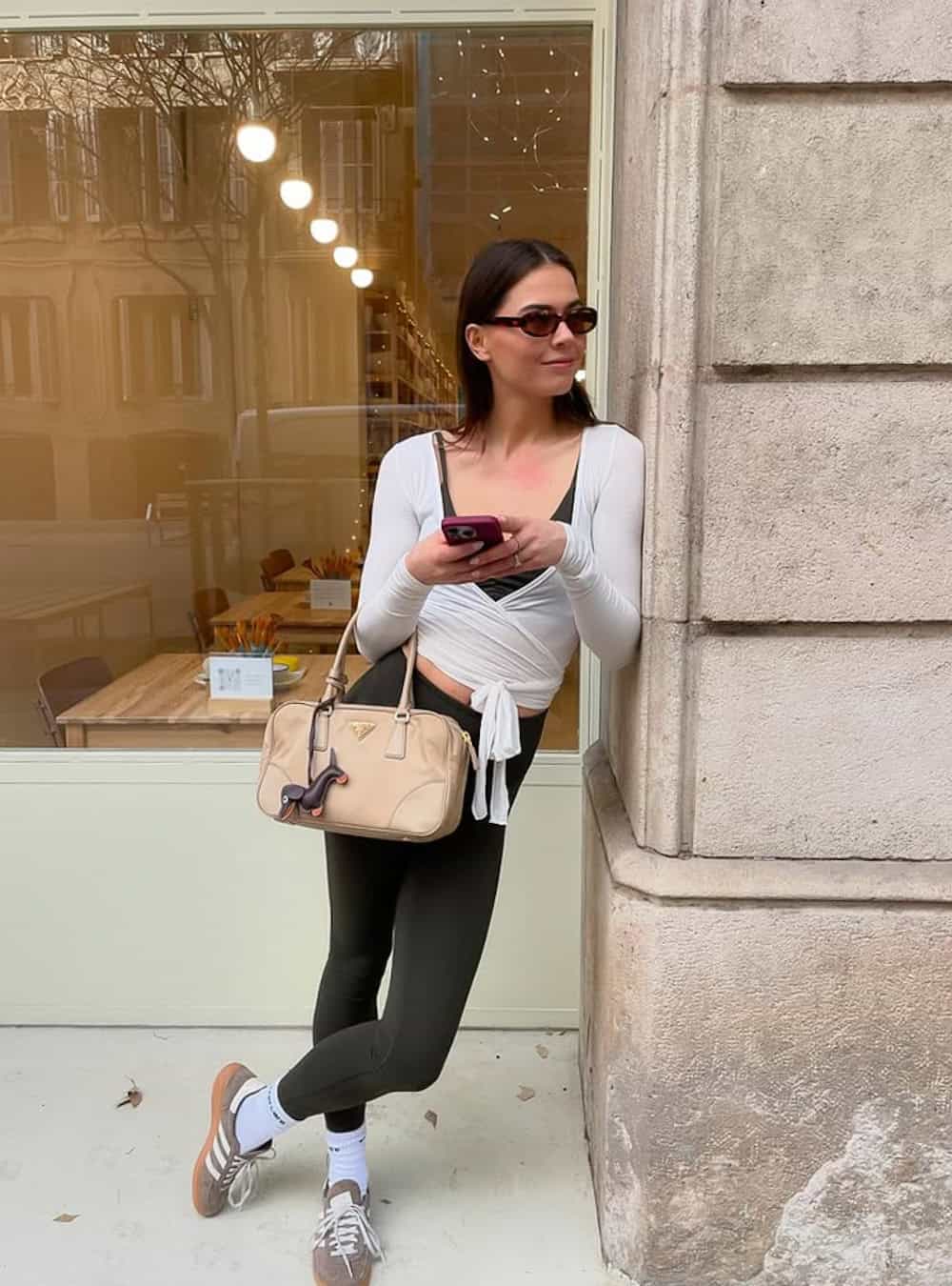 Woman wearing black leggings with a white wrap top and sneakers.