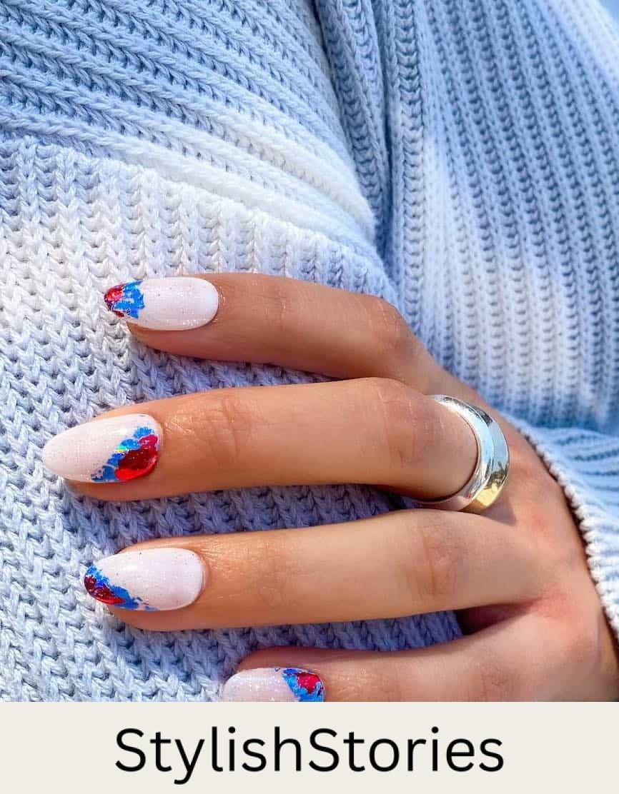 short white almond nails with a glitter topcoat and metallic red and blue foil accents