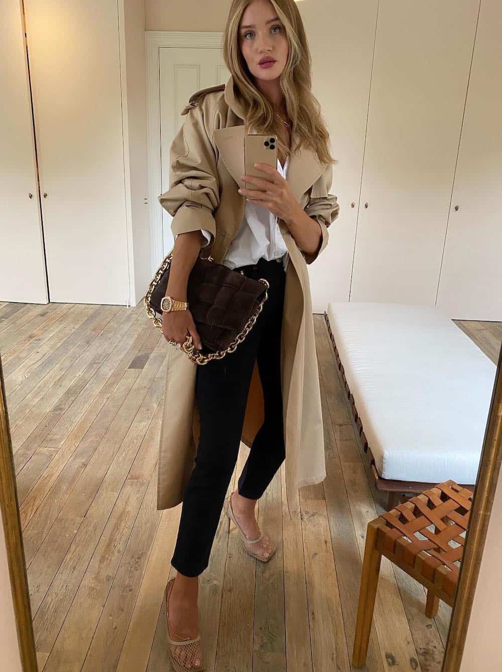 Woman wearing black cigarette pants, heels, a white button down and a trench coat.
