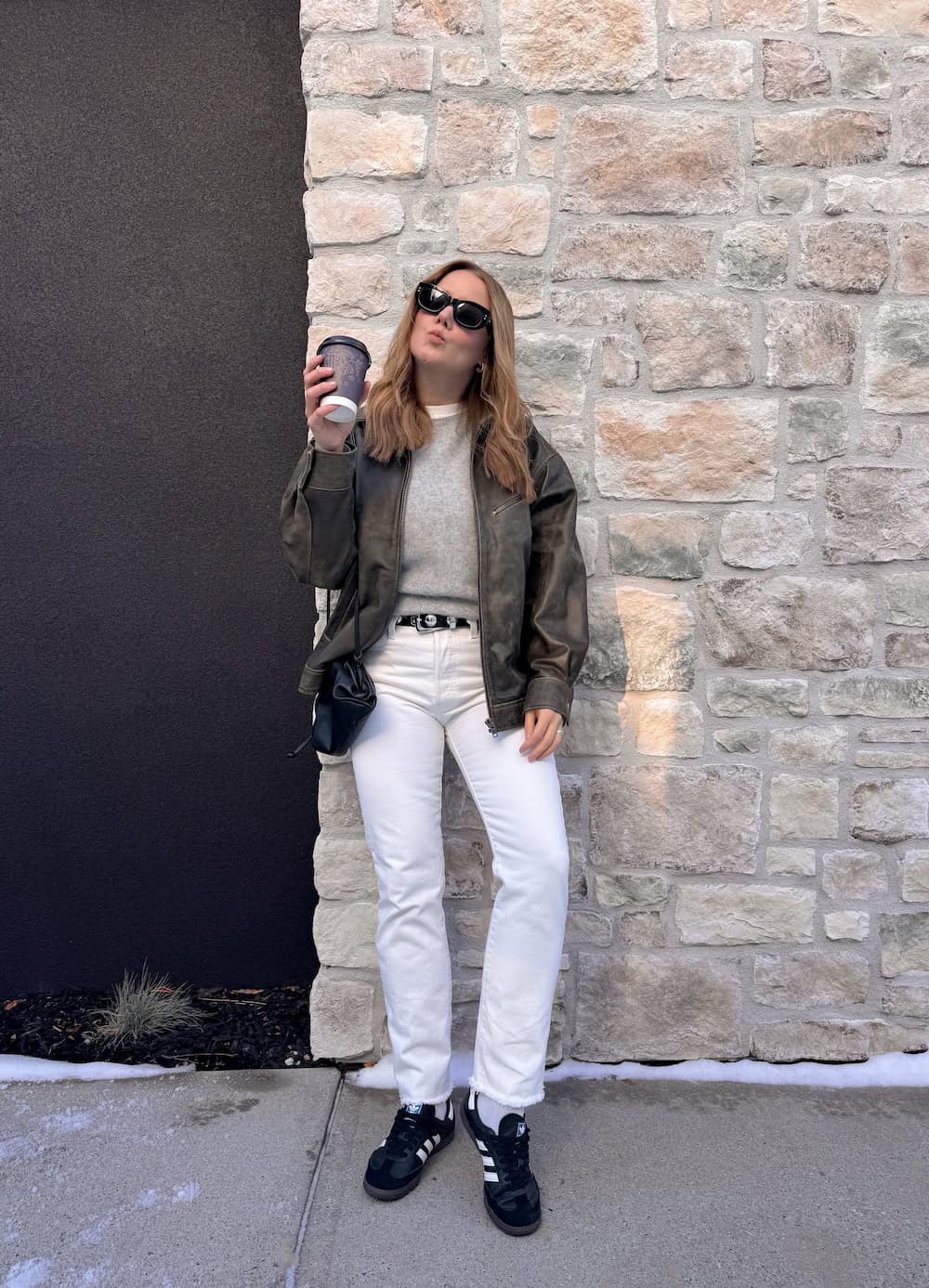 Christal wearing white jeans with a grey sweater and grey jacket with sambas.
