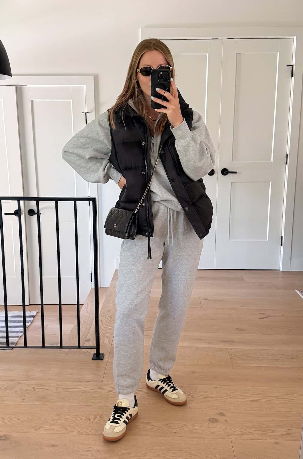 Christal wearing a grey sweat set with a black puffer vest and sambas.