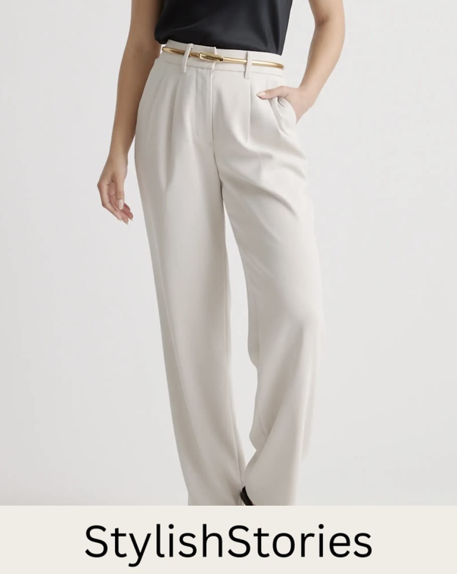Woman wearing a pair of cream pleated wide-leg pants with a gold belt