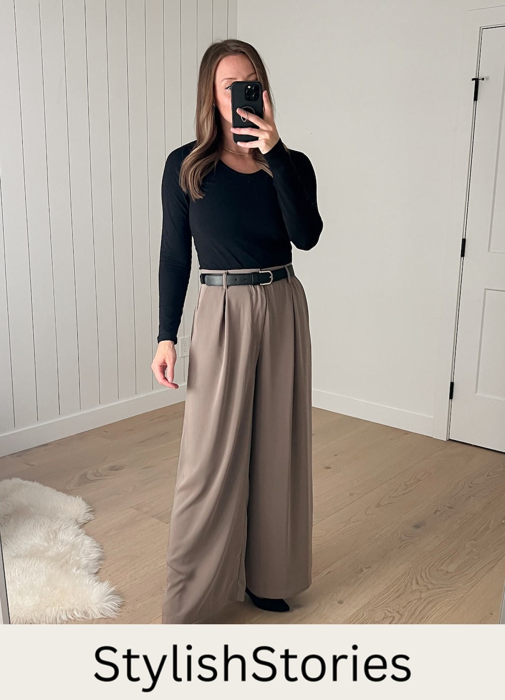 Christal wearing the wide-leg taupe pants with a black long-sleeved top and a black belt with black pumps