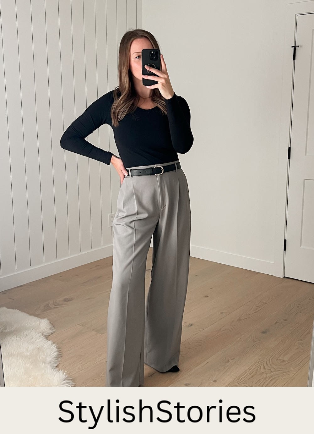 Christal wearing a black long-sleeved top with a pair of grey pleated wide leg pants and black suede pumps
