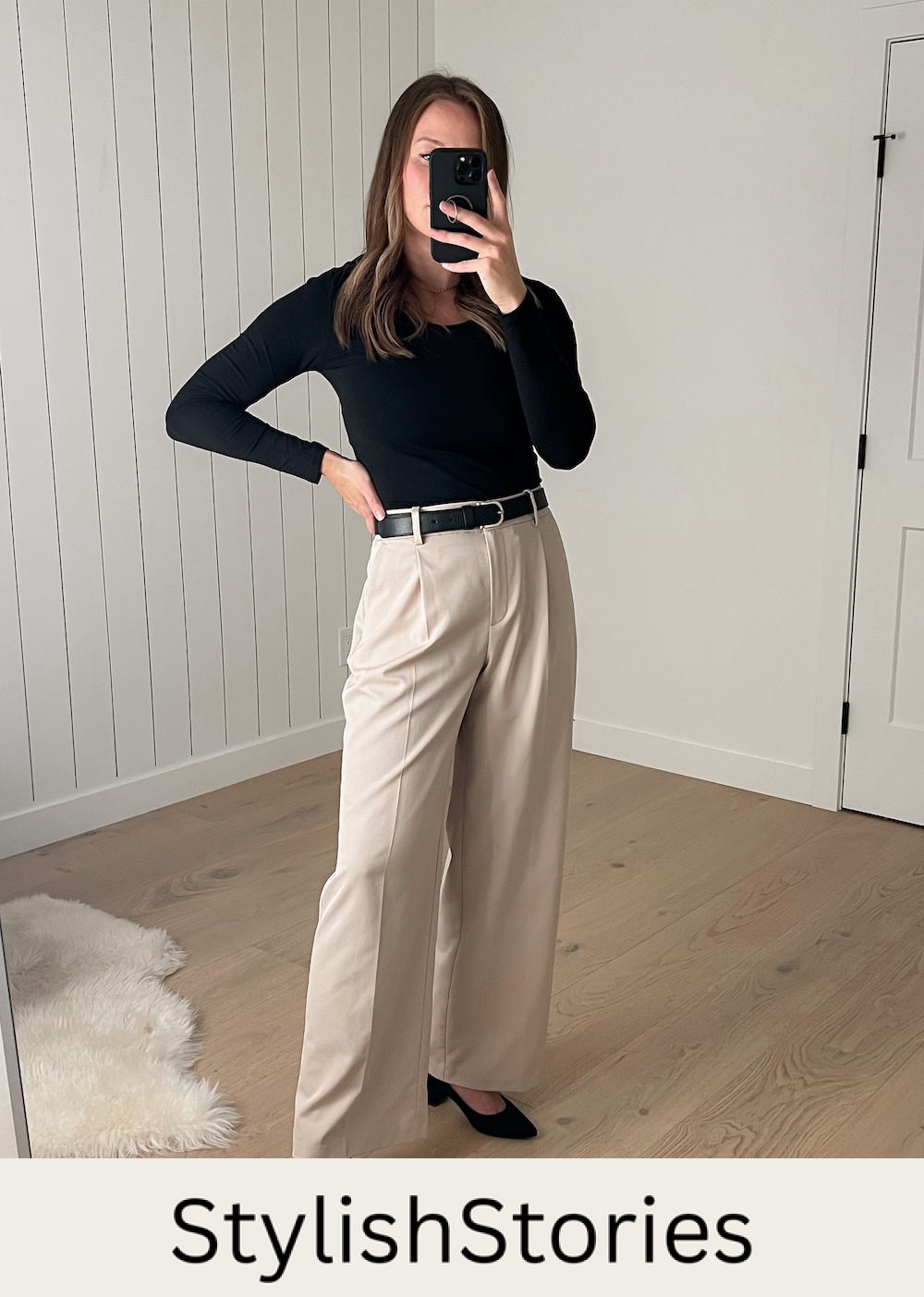 Christal wearing a black long-sleeved top with beige wide-leg pleated pants and black suede pumps
