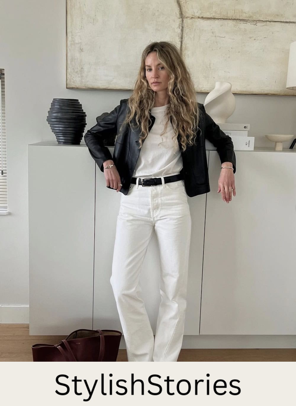 Woman wearing white jeans, black pumps, a white t-shirt and a black leather jacket.