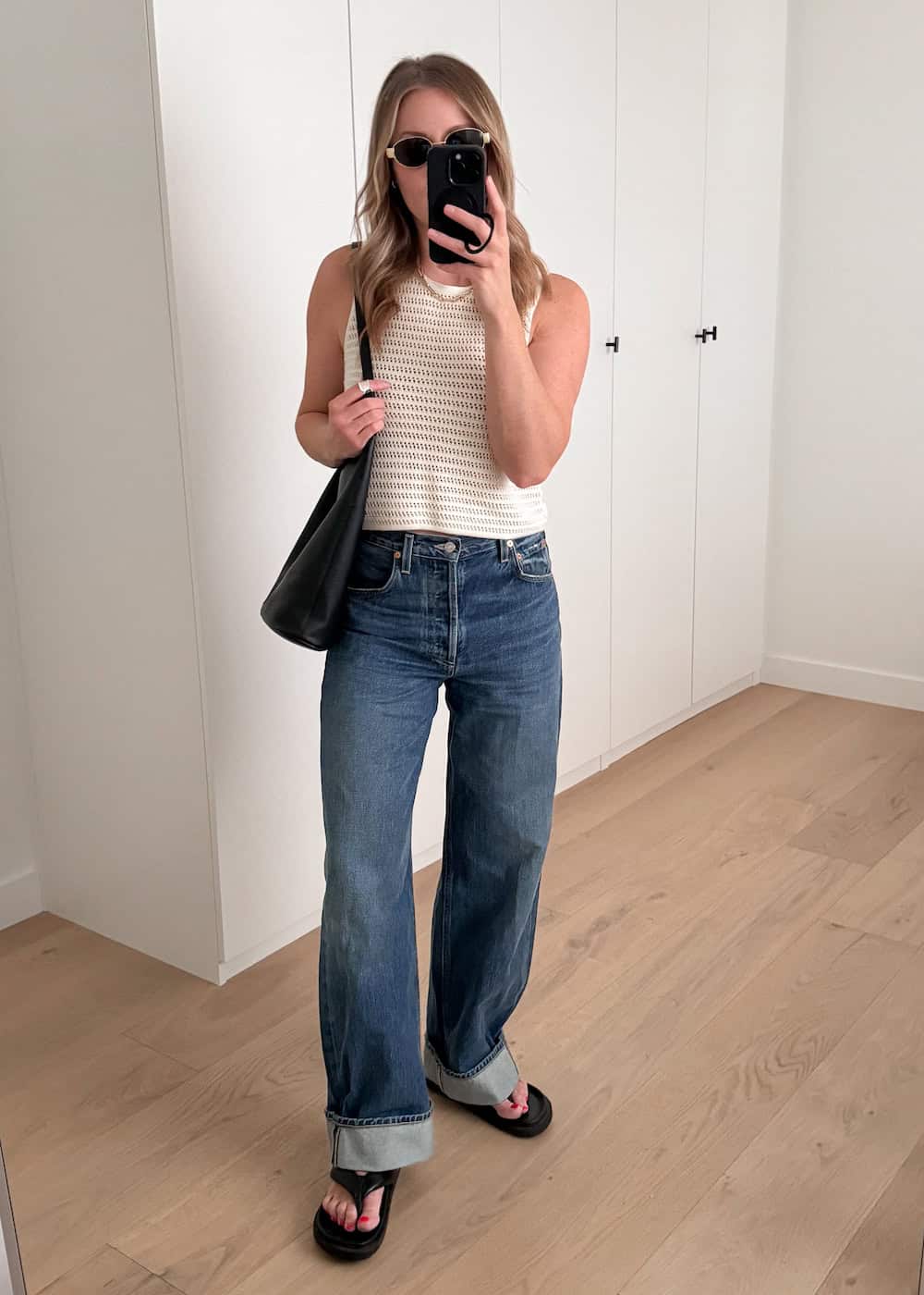 Christal wearing jeans, black sandals and a white crochet tank top.
