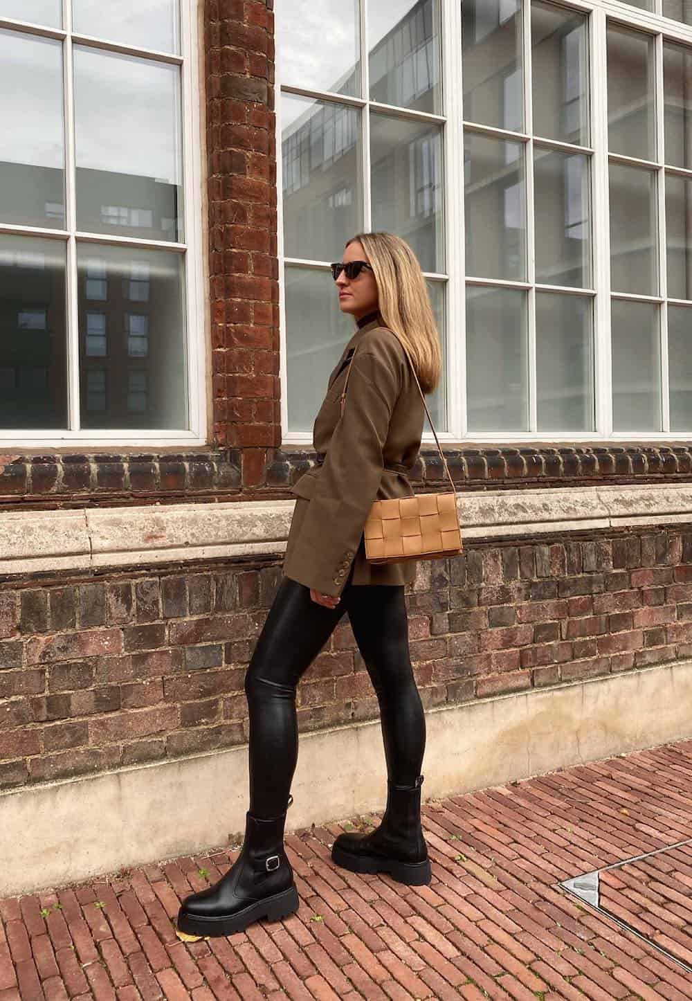 woman wearing a brown blazer with a belt and leather leggings with black boots