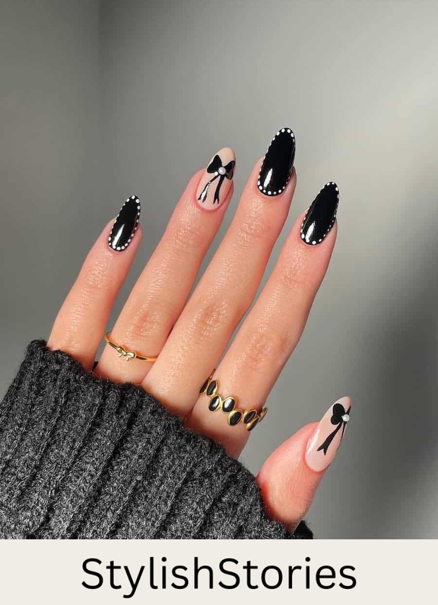 Medium almond nails with black light nails bordered with white dots and two light beige accent nails with black bows and pearl details
