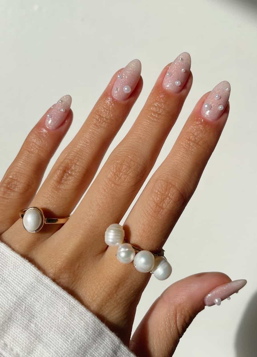 Short almond nails with a white glitter finish and pearl accents