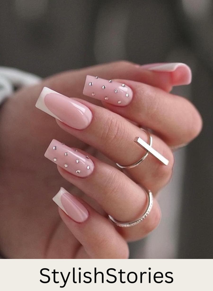 Long square nails painted a soft pink with white tips and two accent nails with crystals