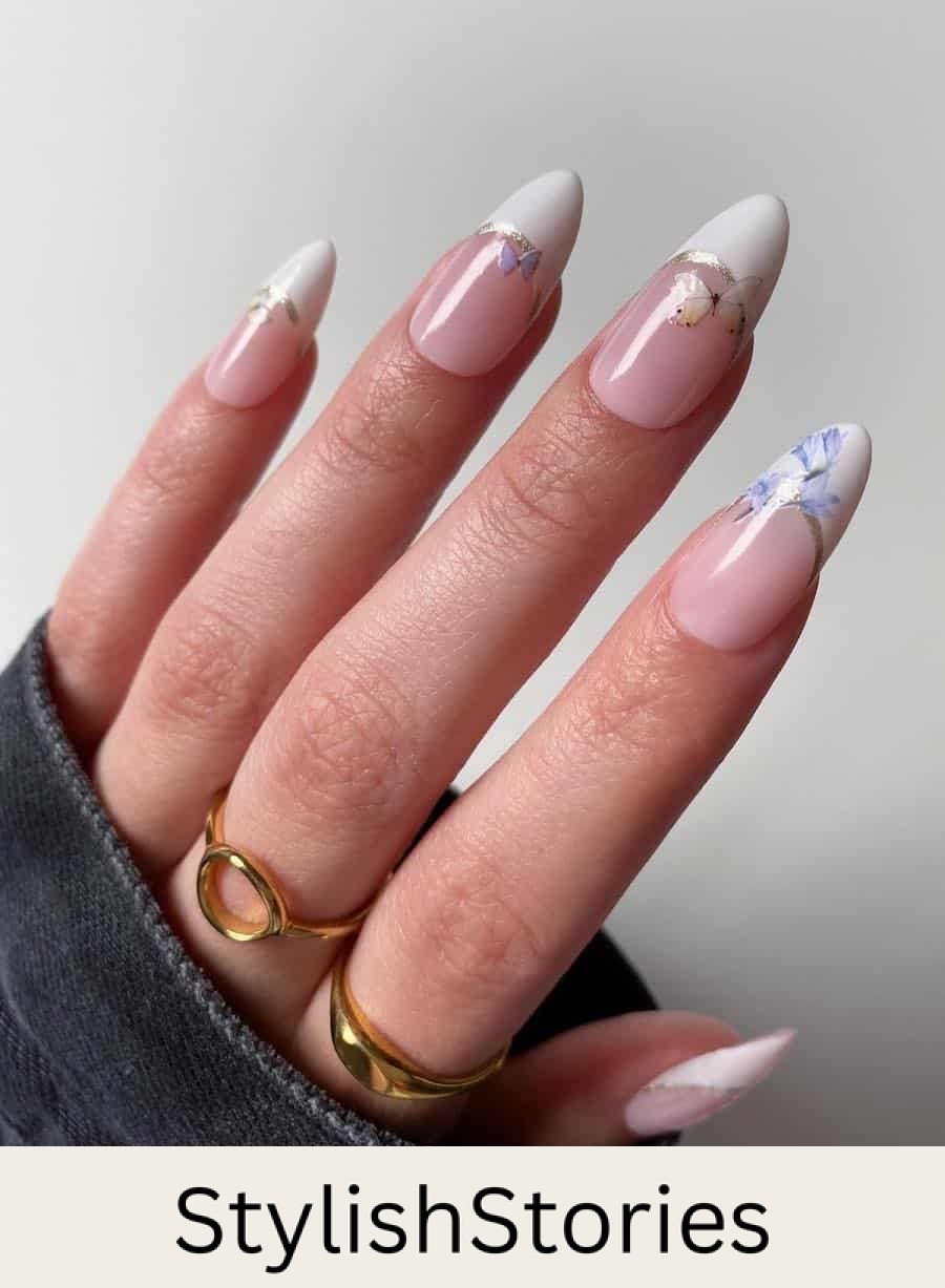Long glossy nude pink almond nails with white tips, silver borders, and floral and butterfly nail stickers