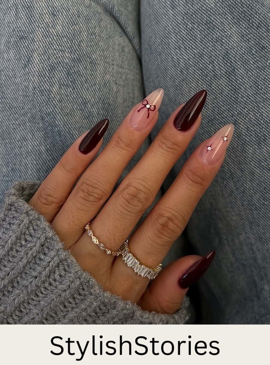 Long almond nails painted a dark brown with nude accent nails featuring dark brown bows and sparkles with gem details
