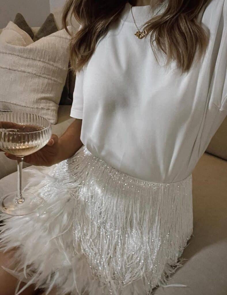 woman wearing a white t-shirt with a white feather mini skirt