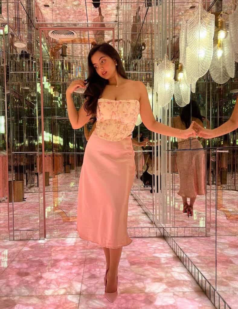 woman wearing a pink floral corset top with a pink slip skirt and heels