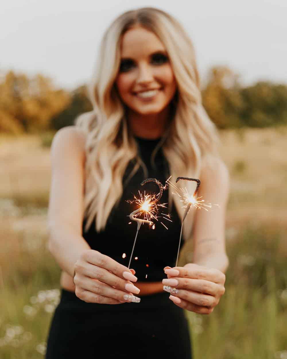 woman holding two sparklers in the number 27 for a birthday photoshoot