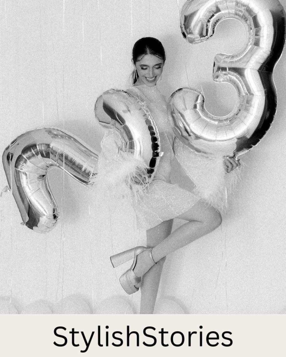 black and white photo of a woman in a sparkly dress holding numbered balloons for a birthday photoshoot 