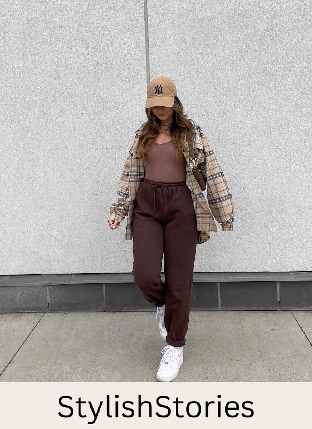 woman wearing a plaid brown shirt with a brown tank and brown sweatpants and white sneakers