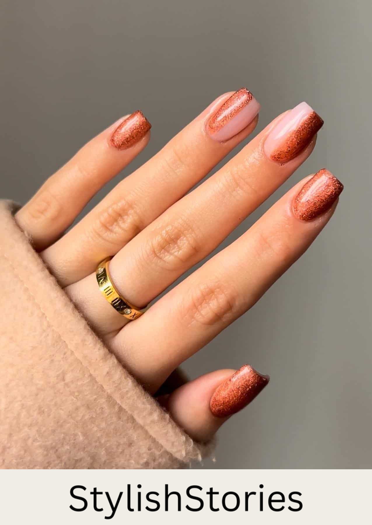 a hand with glittery burnt orange polish with accent nails featuring half polish and half glossy nude