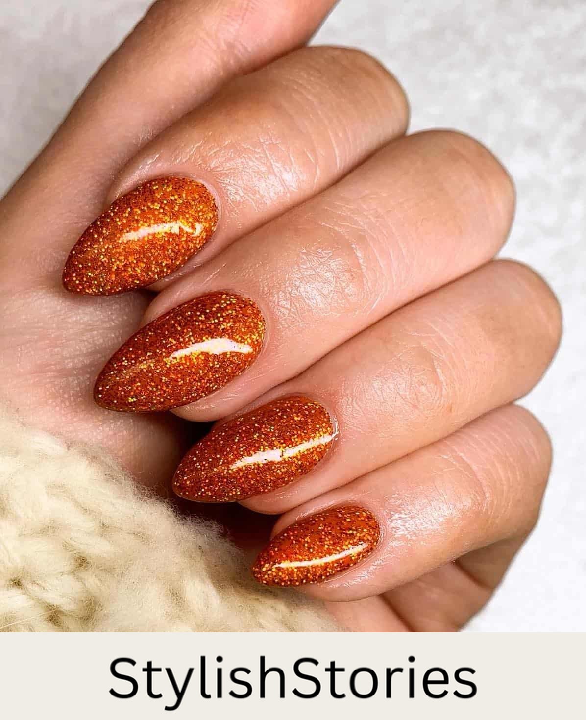 a hand with medium length glittery burnt orange polish