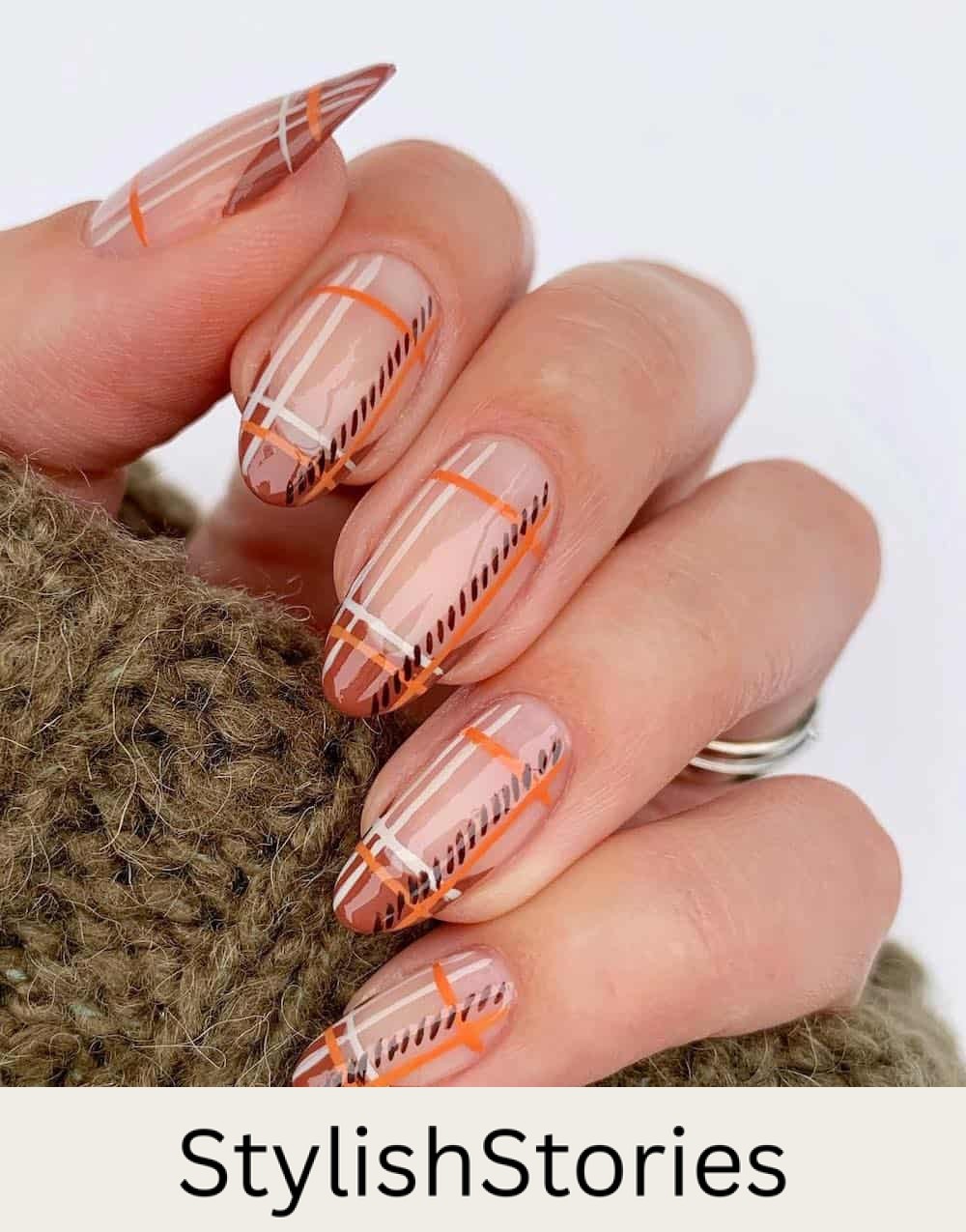 long nude almond nails with a plaid design over burnt orange tips