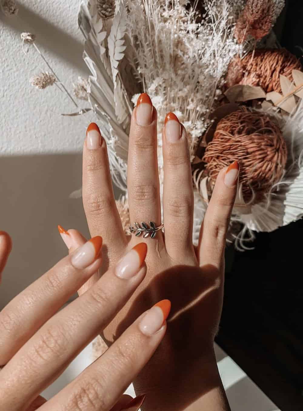 short nude almond nails with burnt orange French tips