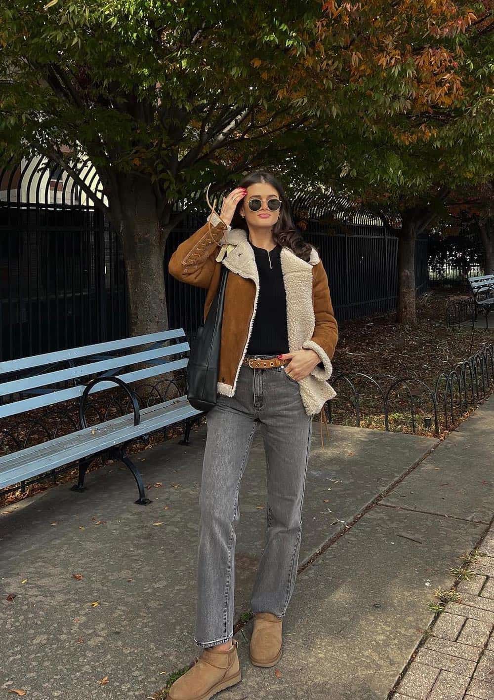 Woman wearing jeans, Uggs, a knit top and a suede and sherpa jacket.