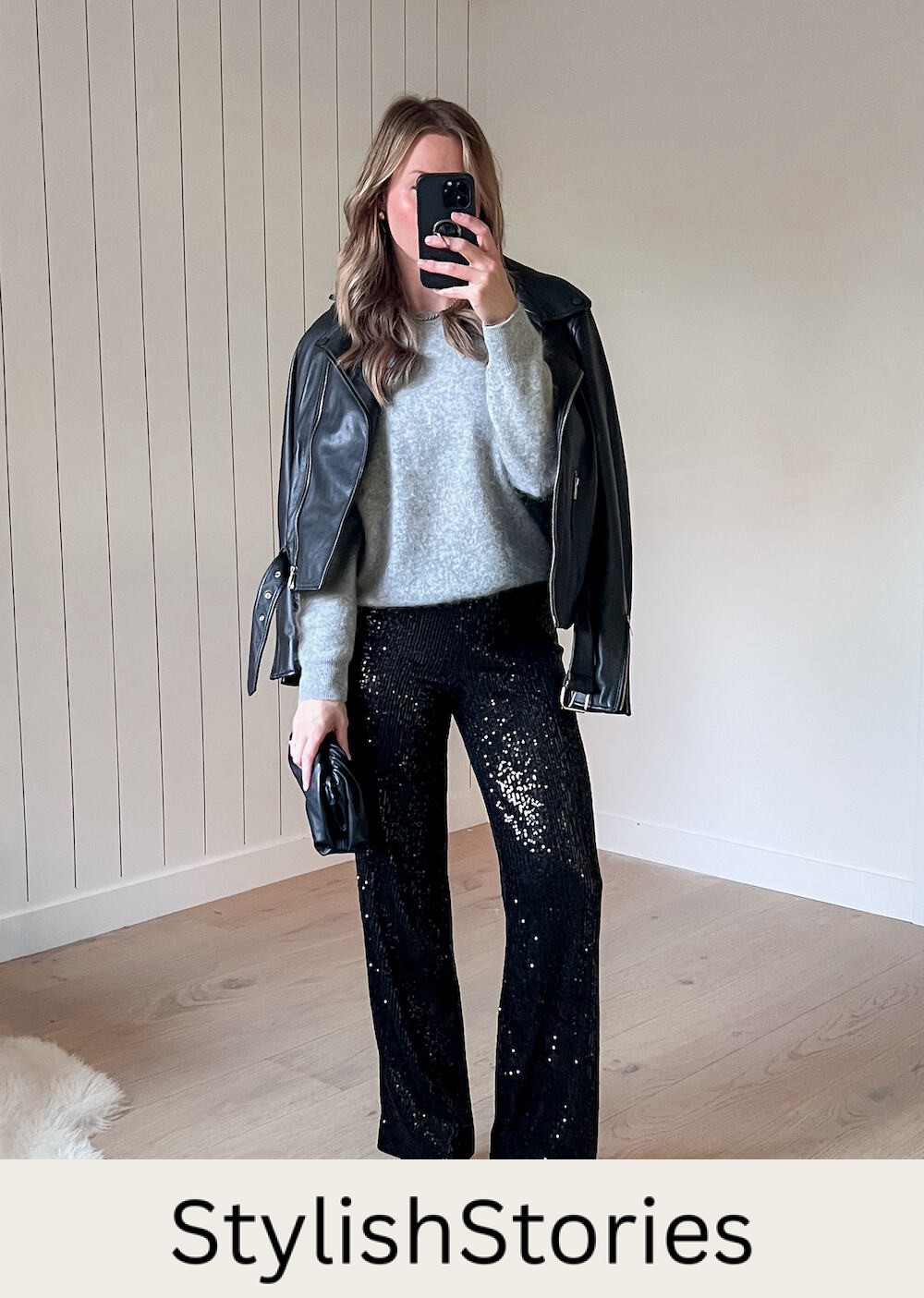 A woman wearing sparkly black wide leg pants with a light grey crewneck sweater, a black leather jacket, and black heels