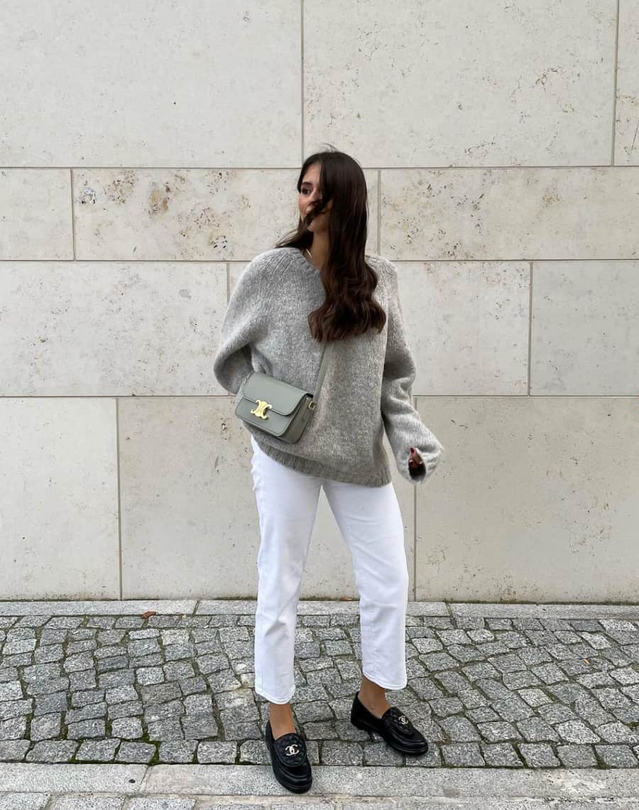 image of a woman in an oversized grey sweater, white Jenas, and black chunky loafers