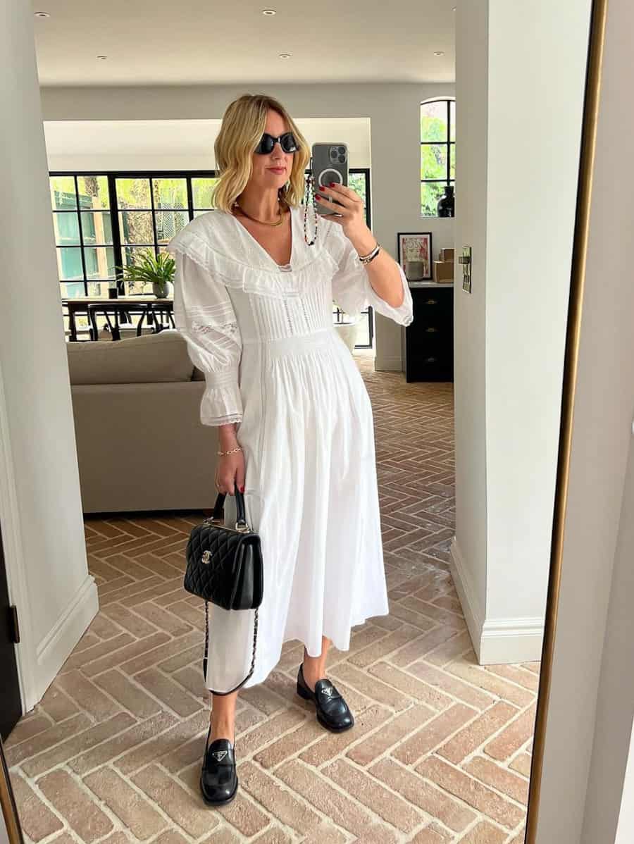 image of a woman in a white midi dress with lace details and puff sleeves and a pair of black loafers