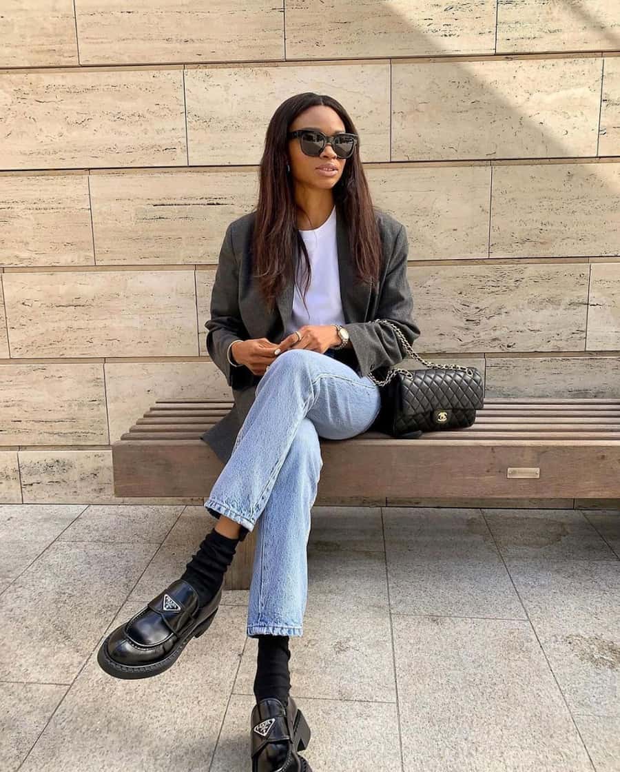 image of a stylish black woman in a grey blazer, basic white t-shirt, jeans, and black loafers with socks