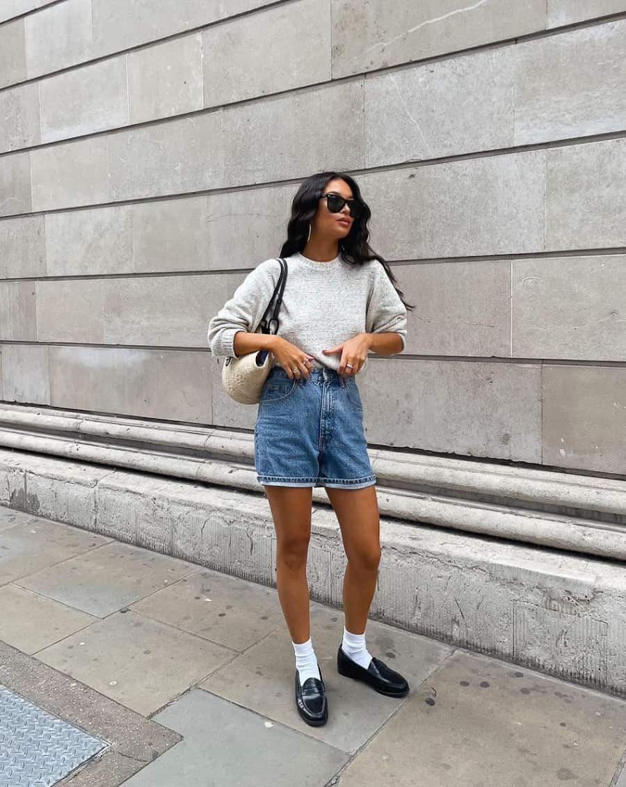 image of a woman in a crewneck sweater, denim shorts, ankle socks, and loafers