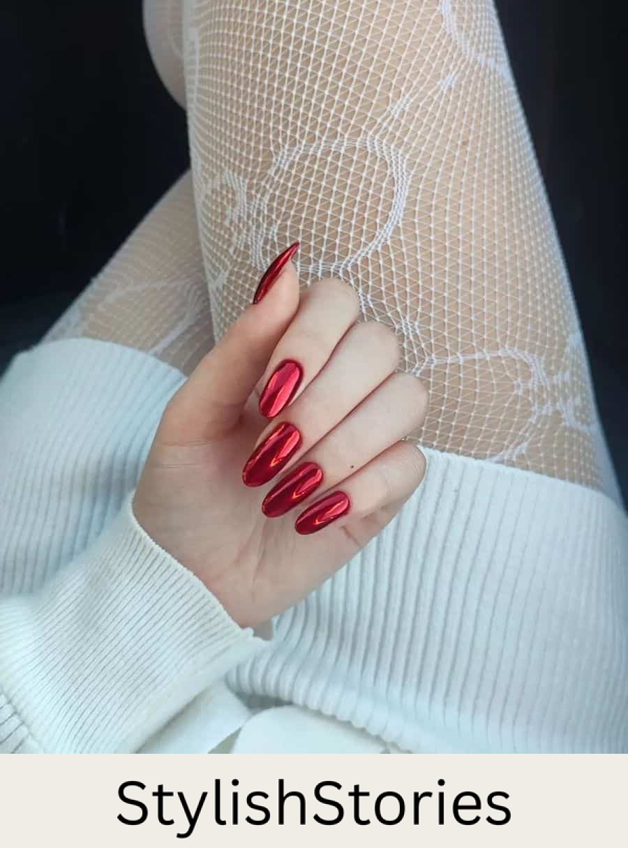 A hand with long round nails painted in red polish with a chrome finish