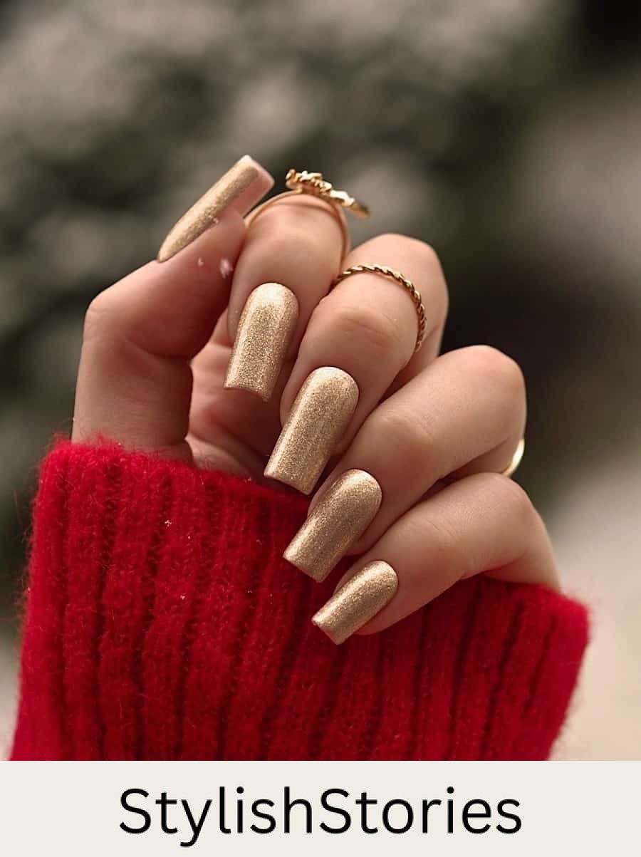 A hand with long square nails painted a gold glitter color