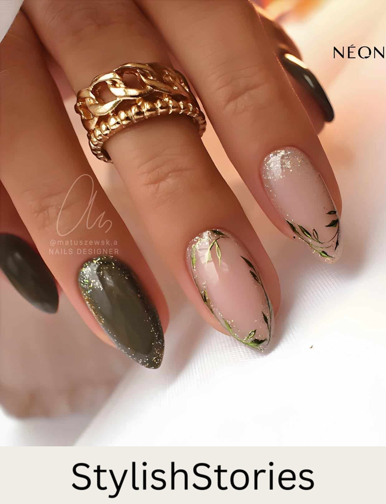A hand with short almond nails painted a dark green with gold accents and two nude accent nails with botanical art