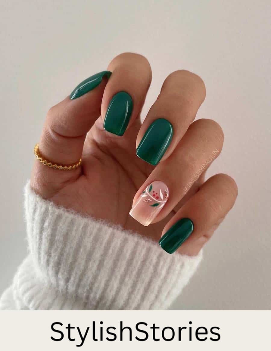 A hand with short square nails painted a deep green with one nude accent nail with colorful botanical art